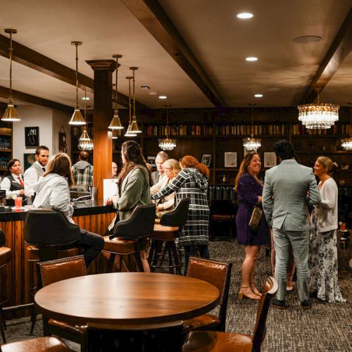 A lively bar scene with people mingling at the counter, chatting in groups, warm lighting, and wooden tables in a cozy lounge atmosphere.