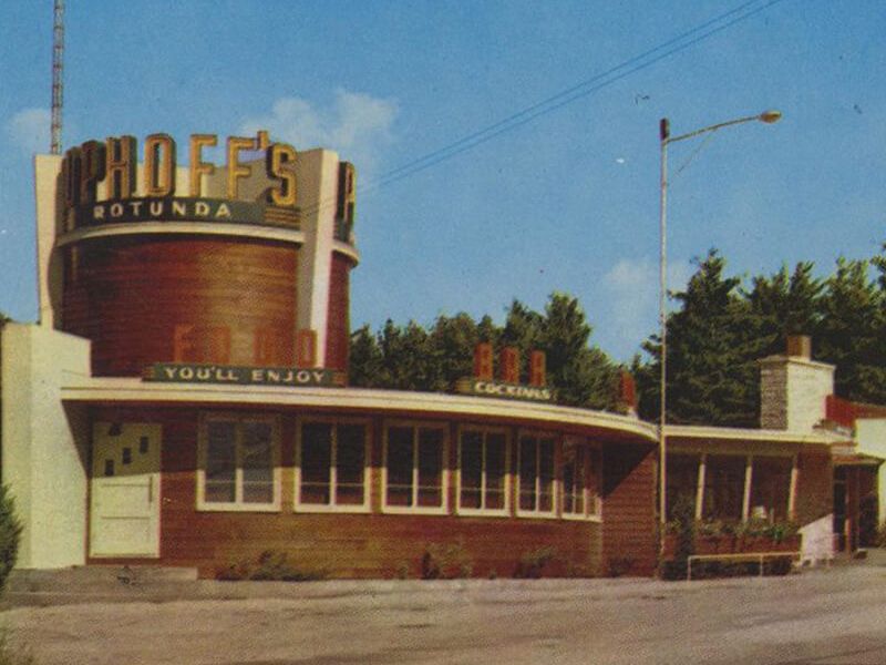 Old-fashioned roadside diner with a curved brick facade, a tall circular sign reading "GODE&rsquo;S" (likely "Godee's" or similar), and retro mid-century styling.