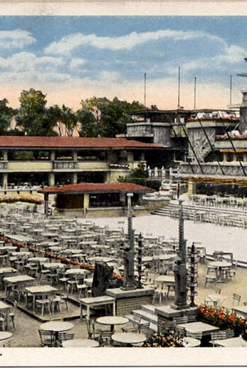 A vintage postcard of Midway Gardens in Chicago, showing rows of empty tables and chairs, a building complex, and a clear sky.
