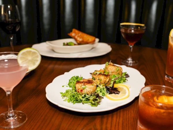 A chic dinner scene: plates with greens and golden-brown shrimp, plus cocktails, candles, and warm lighting creating a cozy, elegant vibe.