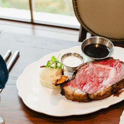A plated steak with pink center, served with a small salad and two dipping sauces on the side.