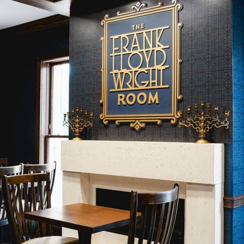 A cozy caf&eacute; corner with wooden chairs and a chalkboard sign reading &ldquo;TARTS&rdquo; beside a window.