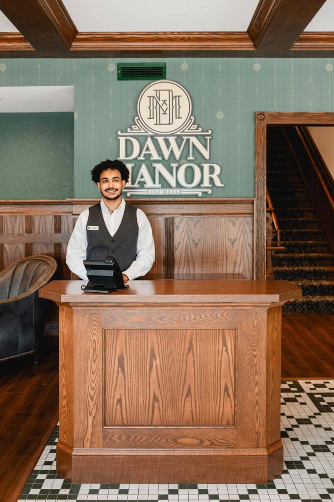 Host smiling at the host stand at Dawn Manor