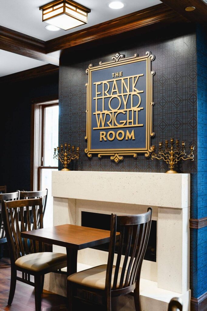 The Frank Lloyd Wright Room sign over modern fireplace and a table for two
