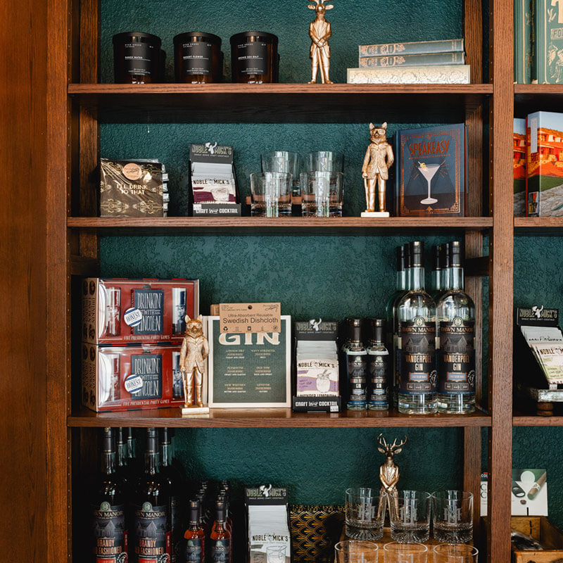 Dawn Manor branded glassware, alcohol, and other gifts on shelves at the Sundries Shoppe